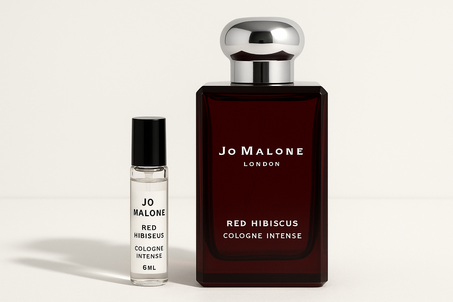 Jo Malone Red Hibiscus Cologne Intense 6 ml campione standing next to 100 ml perfume bottle of Jo Malone Red Hibiscus Cologne Intense which has white writing on dark red bottle